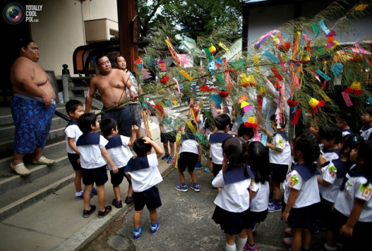 Մանկապարտեզի երեխաները սումոյի մարտիկներին նվիրում են ժապավեններով զարդարված բամբուկի ճյուղ