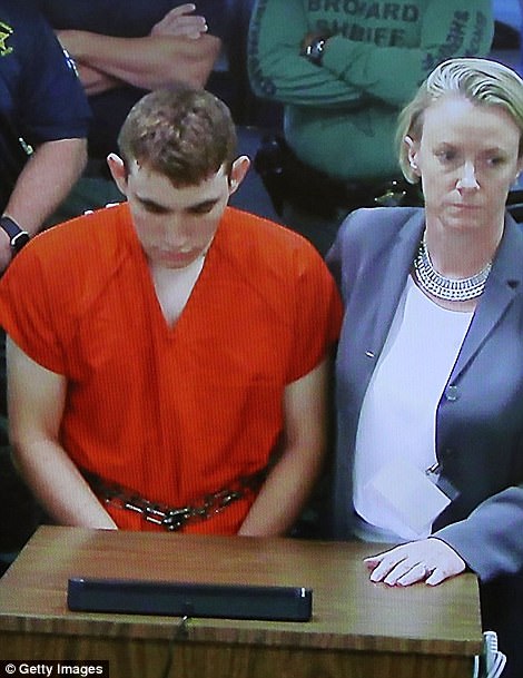 Public defender puts arm around shackled and cowering Florida gunman at his first court appearance: 'White supremacist' is silent as he is ordered to be held without bond for killing 17 people