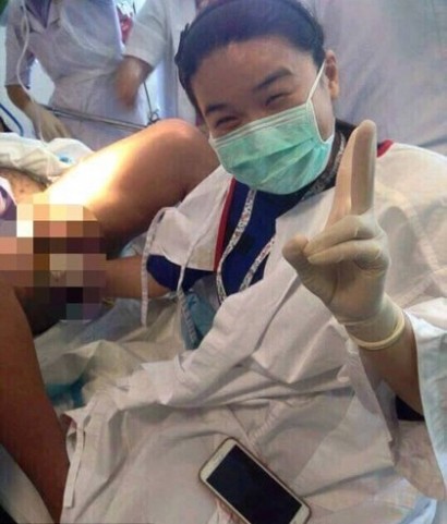 Obscene moment a female doctor poses for a SELFIE and flashes the 'peace' sign while delivering a baby