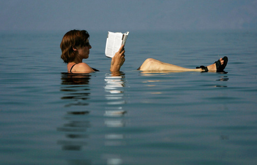 Туристка из Германии читает путеводитель в водах Мёртвого моря, 4 июня 2005 года.